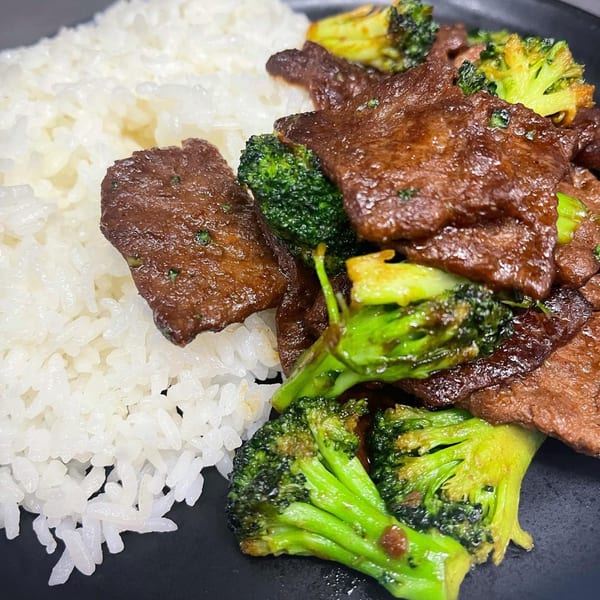 Lazi Cow's beef and broccoli stir-fry with white rice on a black plate.